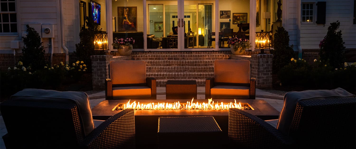 A beautiful outdoor landscaping project with firepit and lighting designed and built by R&R Landscaping.