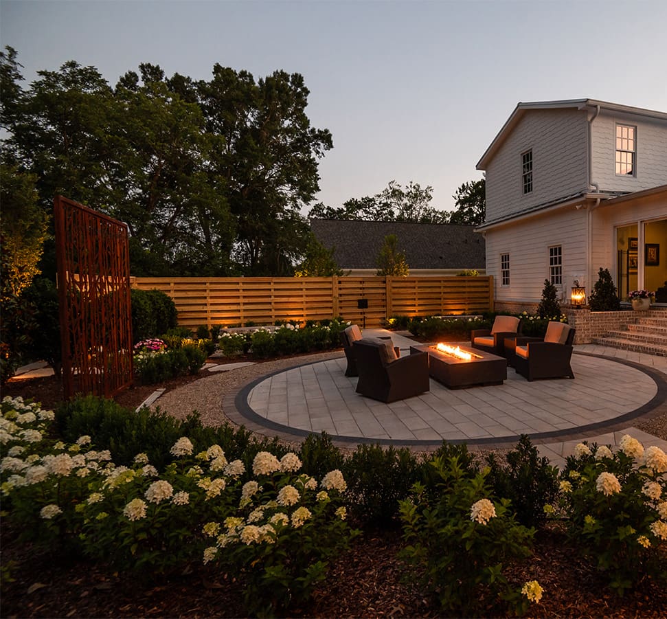 A beautiful outdoor living space with lighting and fire pit, designed and installed by R&R Landscaping