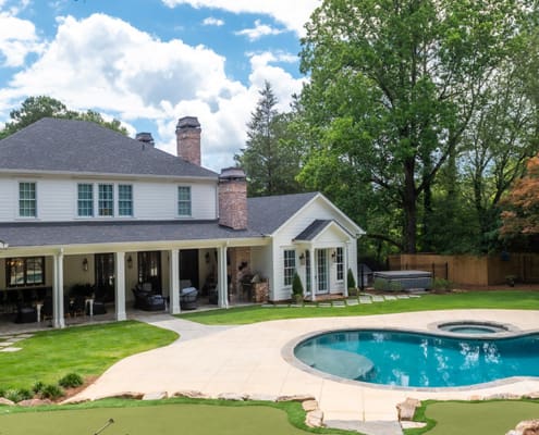 A resort-style backyard with beautiful plants, a swimming pool, fire pit, and putting green. This landscape was designed and built by R&R Landscaping.