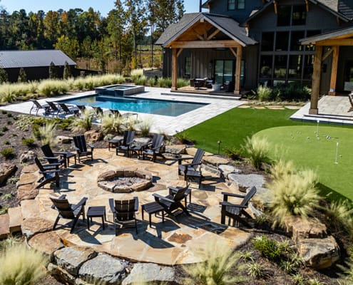 A large, beautiful outdoor space that includes a swimming pool, putting green, full-sized soccer field, multiple tee boxes to practice golf, and a spectacular sitting area. This landscape was designed and built by R&R Landscaping.