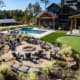 A large, beautiful outdoor space that includes a swimming pool, putting green, full-sized soccer field, multiple tee boxes to practice golf, and a spectacular sitting area. This landscape was designed and built by R&R Landscaping.