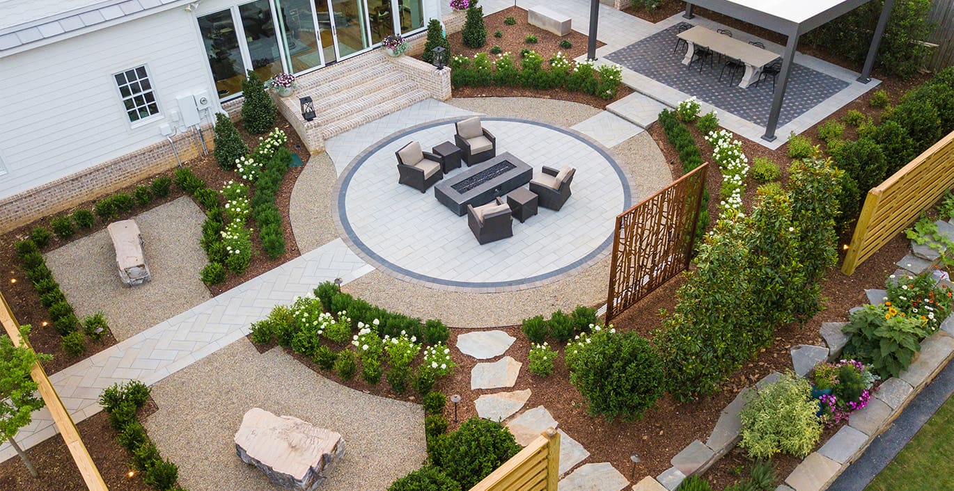 R&R Landscaping A classic landscape design with modern twists, including a fire pit, beautiful plants and shrubs, a covered dining table, and custom rock benches engraved with the family's favorite quotes. This outdoor living space was designed and built by R&R Landscaping.