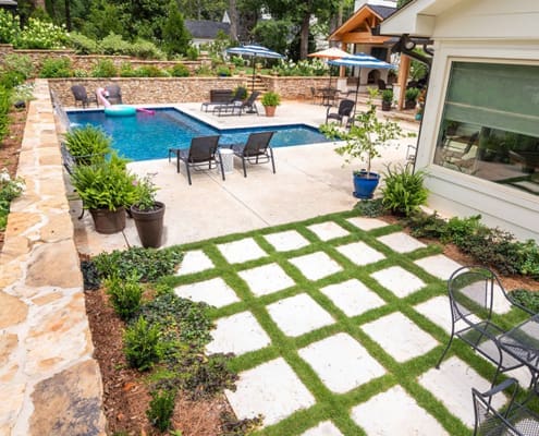 A beautiful resort-inspired landscape with unique drainage solutions, complete with layered plant walls, year-round seasonal color, and new sod for a landscape built to last. This project was designed and built by R&R Landscaping.