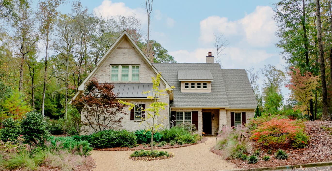 Craftsman-style home framed by mature trees and layered foundation plantings
